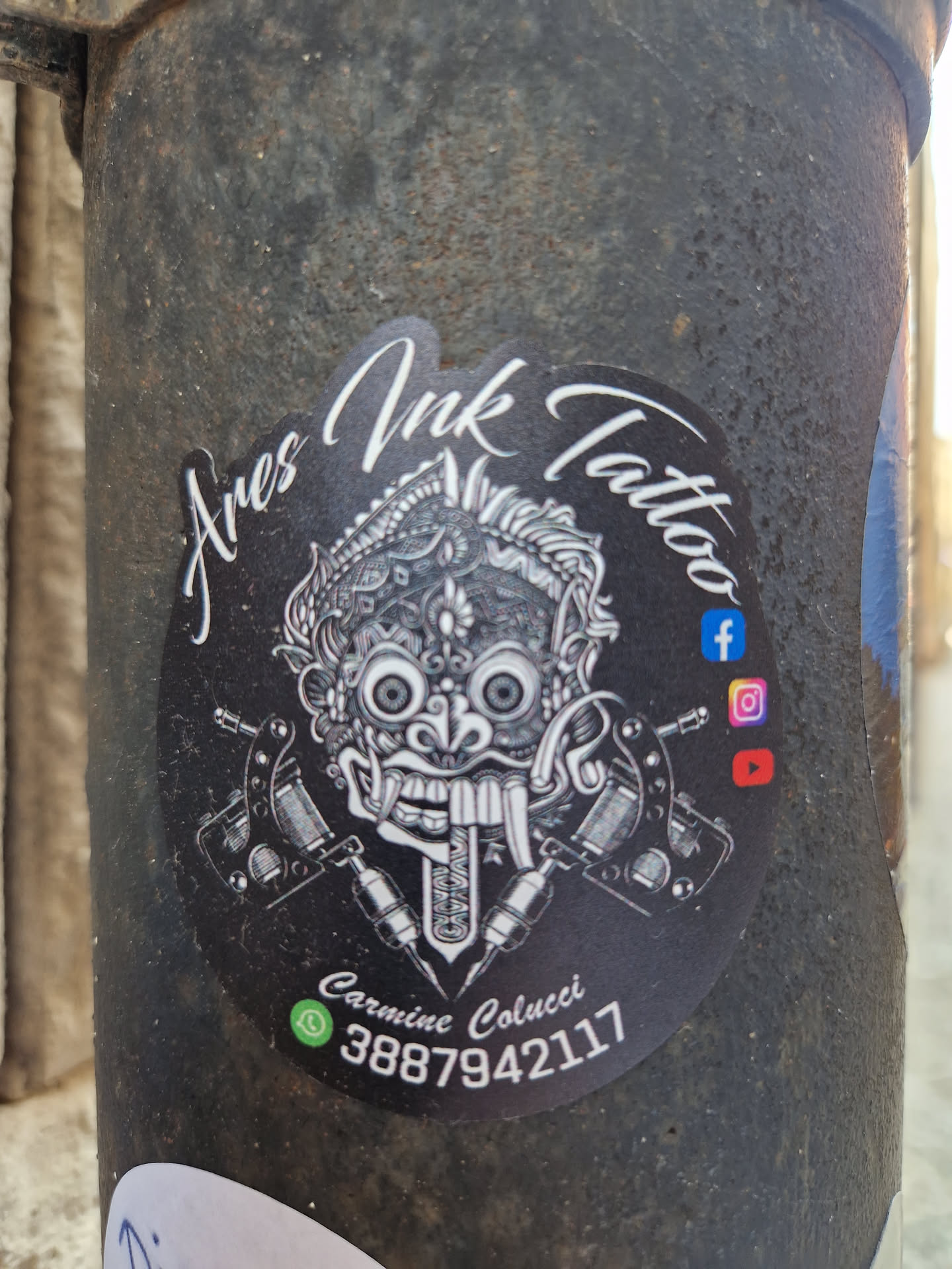 Black and white sticker with a Barong mask illustration, tattoo machines, and contact info. 