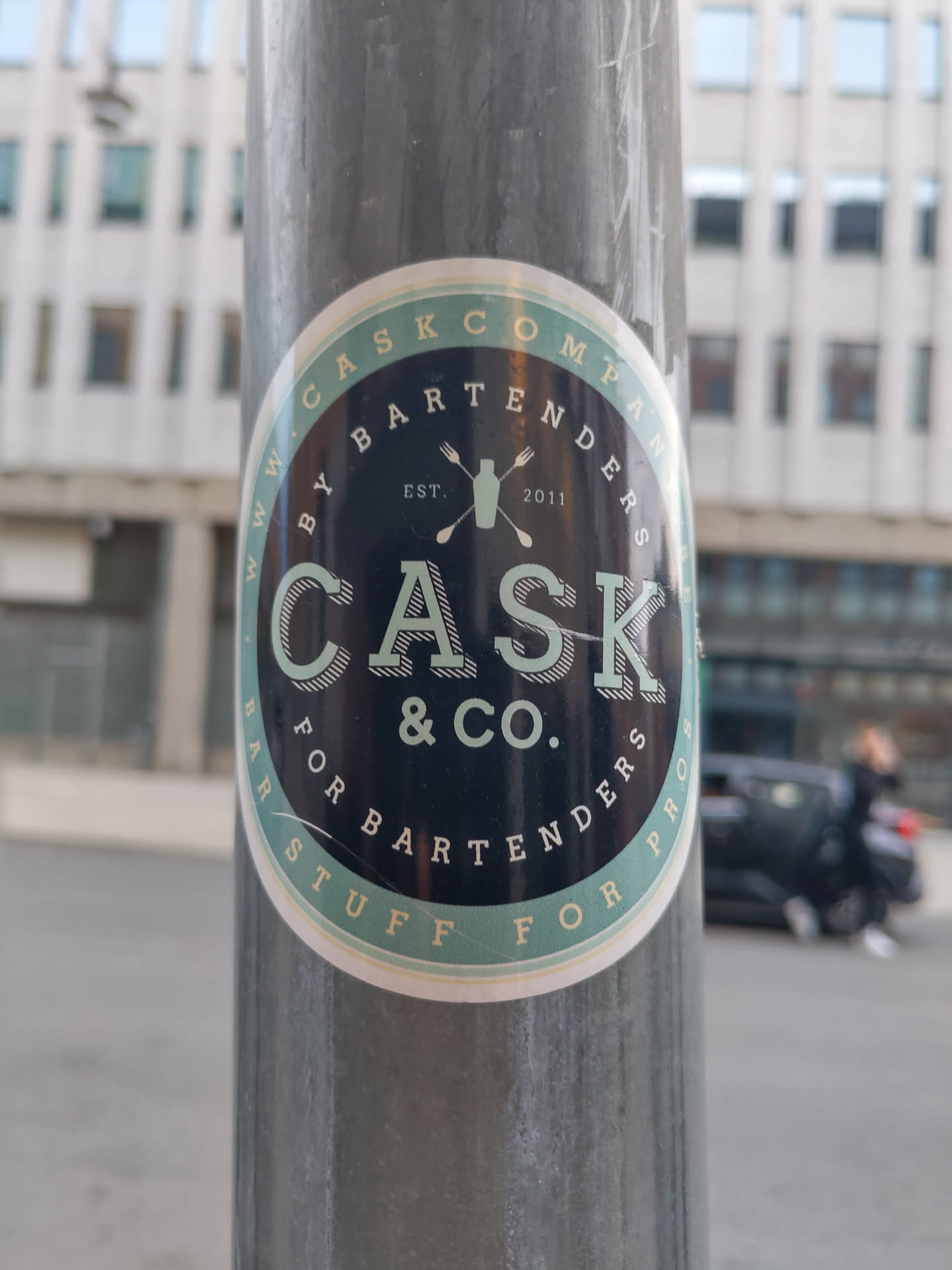 A round sticker with a dark-blue background and light-green circular border.  It features the logo for Cask & Co., a company that provides products for bartenders.  The text on the sticker reads "www.caskcompany.com by bartenders for bartenders est. 2011 cask & co. ".  A cocktail shaker icon is also present in the design.