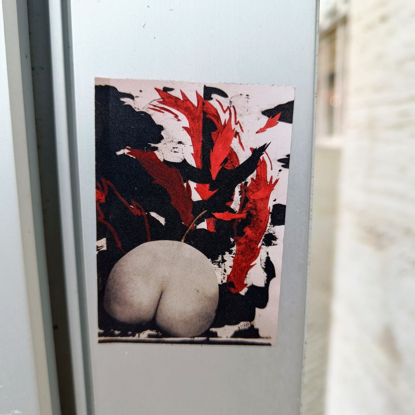 A sticker featuring an abstract artwork dominated by red and black brushstrokes. A light-colored pear is prominently positioned in the center, partially obscured by the abstract elements.  The style is reminiscent of expressionism or abstract expressionism.