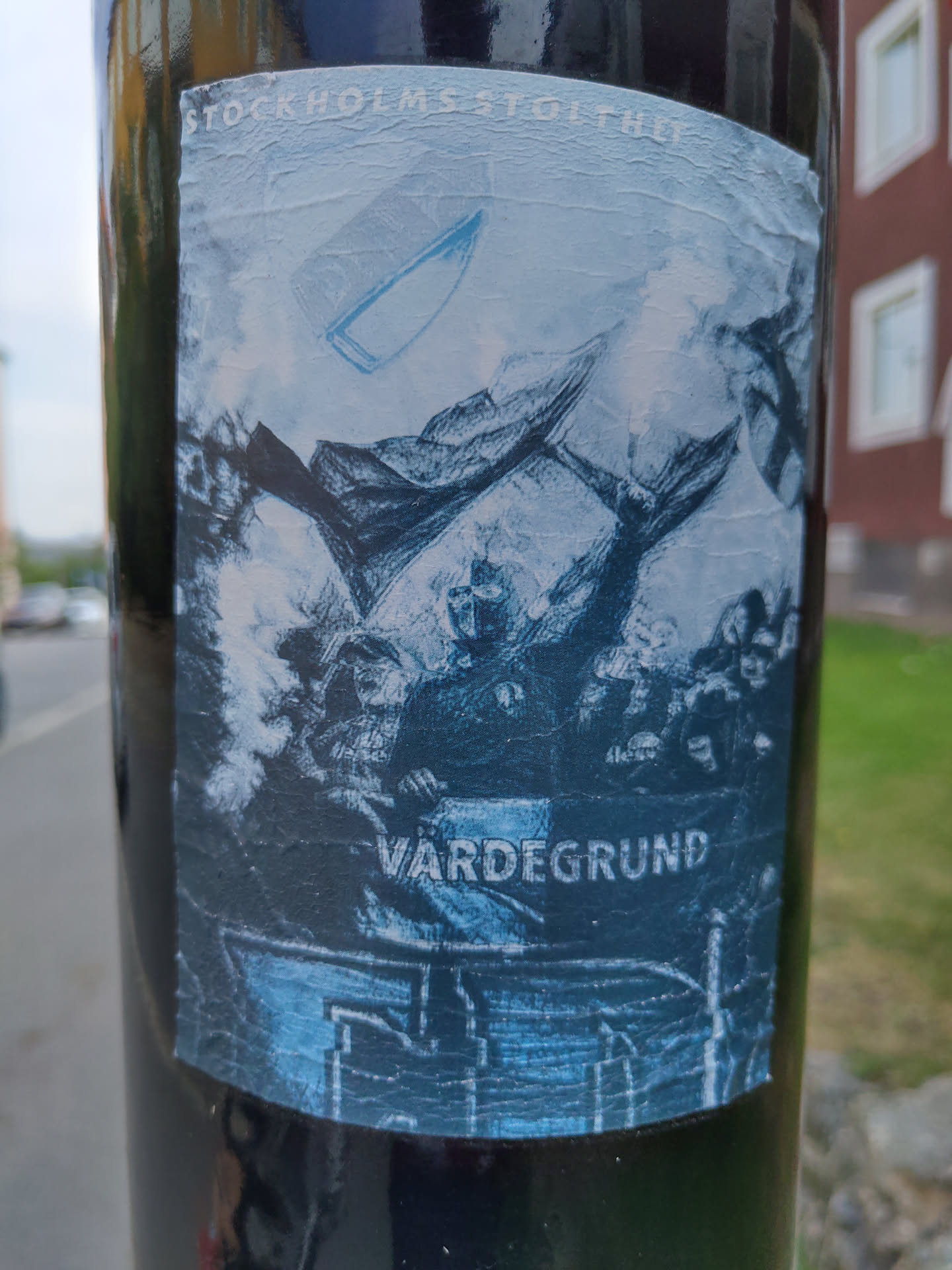 A sticker featuring a stylized image, possibly referencing Stockholm's history or culture. The central motif appears to be a historical scene with figures and a boat, rendered in shades of blue and grey.  The text 'Vardegrund' is visible at the bottom.