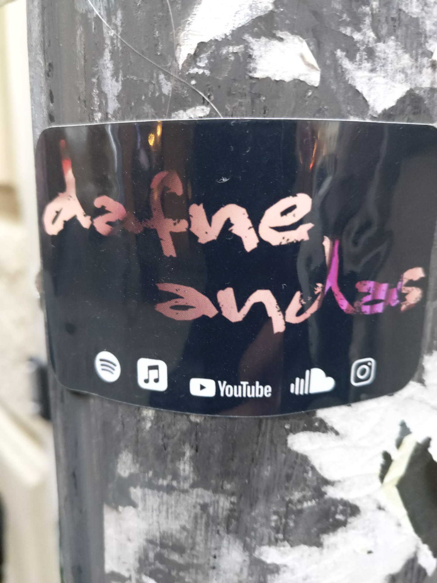 Black sticker with the text "dafne and klaus" written in pink and white.  At the bottom, there are social media icons for Spotify, Apple Music, YouTube, SoundCloud, and Instagram.