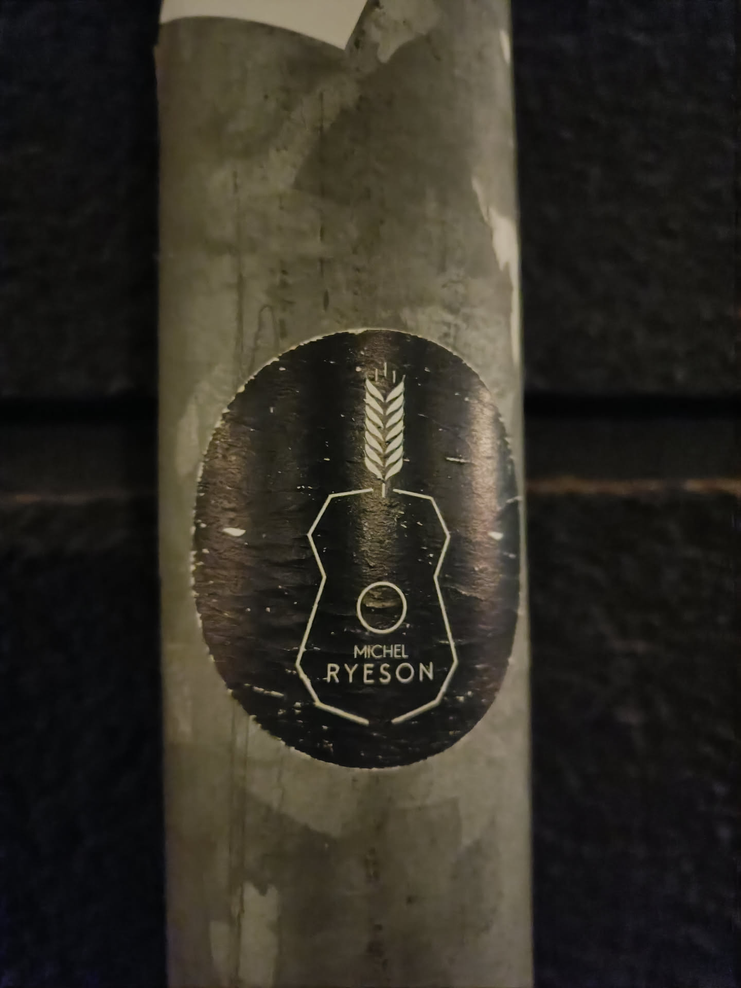 A black and white sticker with a unique design featuring a wheat stalk and geometric shapes. The artist's name, Michel Ryeson, is prominently displayed.