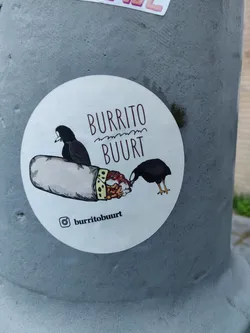 A round sticker featuring a cartoon burrito being eyed by two birds. The text 'Burrito Buurt' is prominently displayed, along with an Instagram handle.