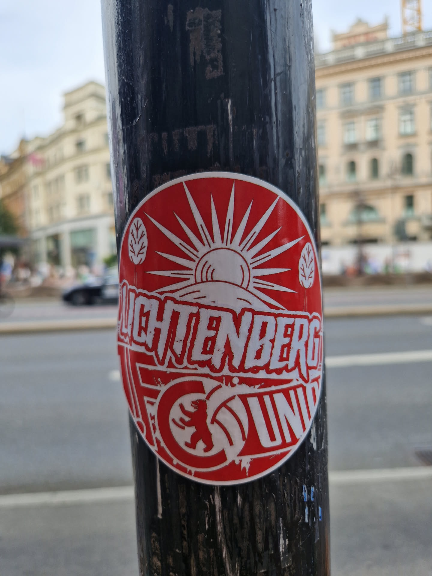 Red and white circular sticker featuring a stylized sun, mountains, and the text "Lichtenberg Union."  A bear graphic is prominently displayed at the bottom. The sticker appears to be promoting a group or organization.