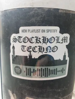 A sticker featuring a playlist for Stockholm Techno music on Spotify. It has a cityscape silhouette and a Spotify code.