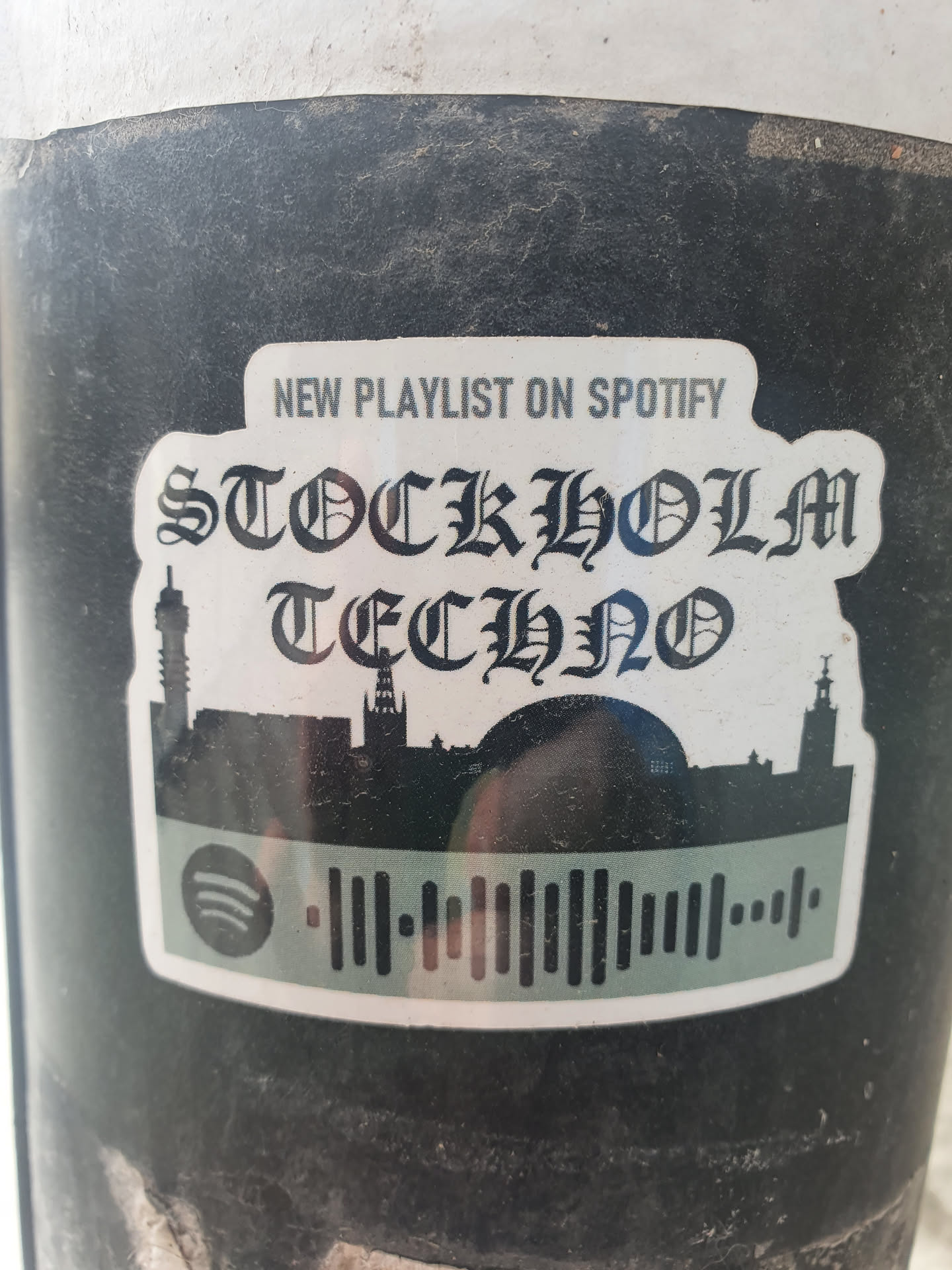 A sticker featuring a playlist for Stockholm Techno music on Spotify. It has a cityscape silhouette and a Spotify code.