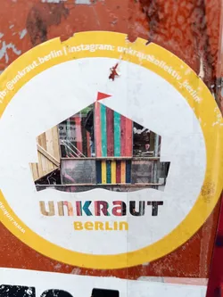 Round yellow and white sticker with the text Unkraut Berlin and an image of a colorful building. The sticker also contains social media handles.