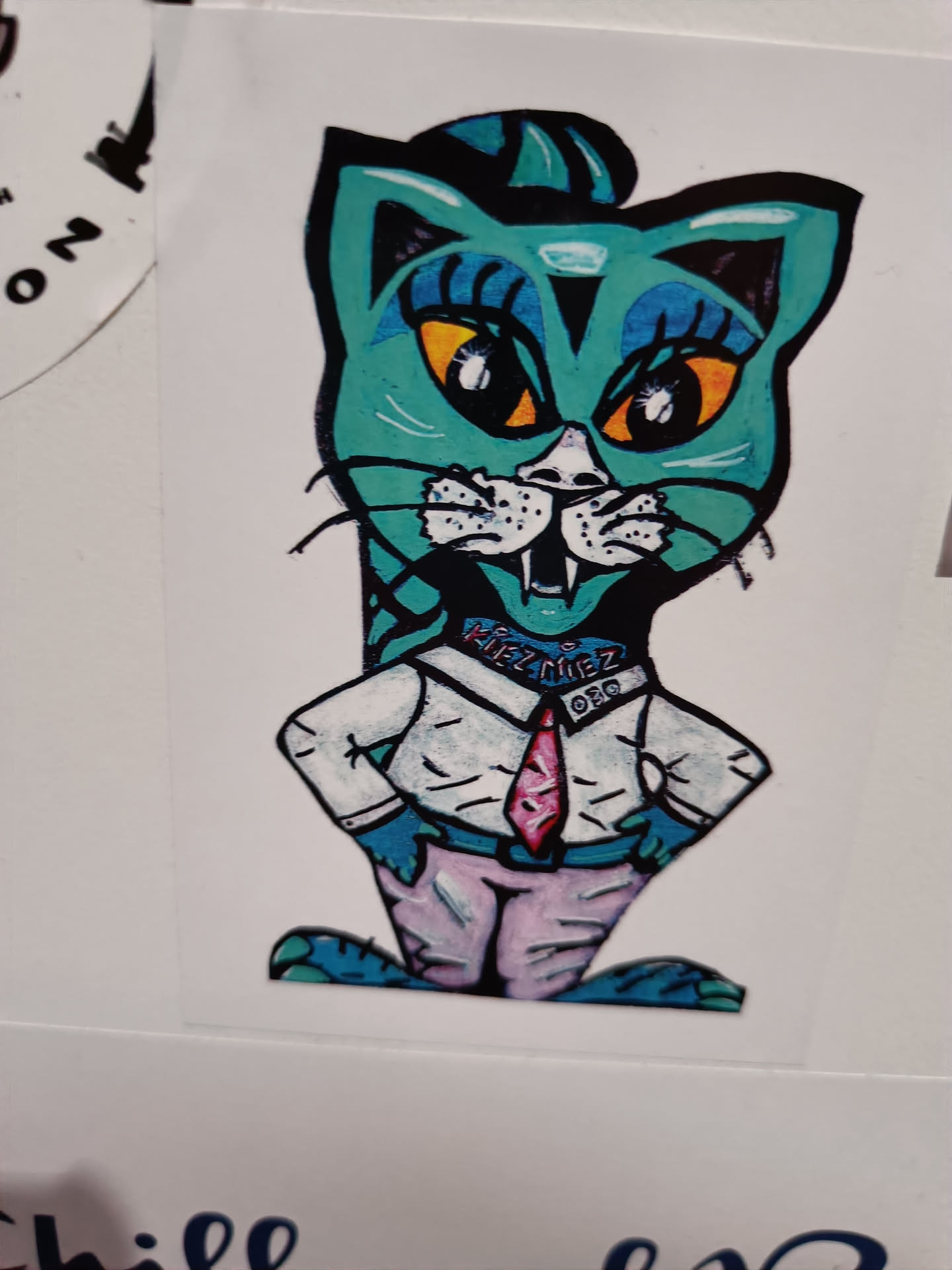 This sticker features a teal cat wearing a collared shirt and tie. The cat has exaggerated features, including large eyes and a stylized hairdo. The art style is reminiscent of cartoons or graffiti art.