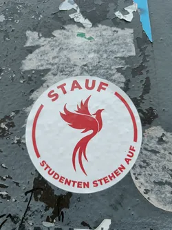 Round sticker with a red phoenix and the text "STAUF" above and "STUDENTEN STEHEN AUF" below the phoenix. The text translates to "Students rise up!" in German.