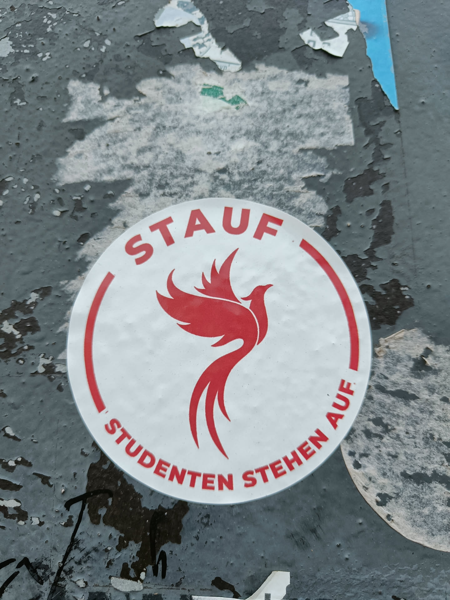 Round sticker with a red phoenix and the text "STAUF" above and "STUDENTEN STEHEN AUF" below the phoenix. The text translates to "Students rise up!" in German.