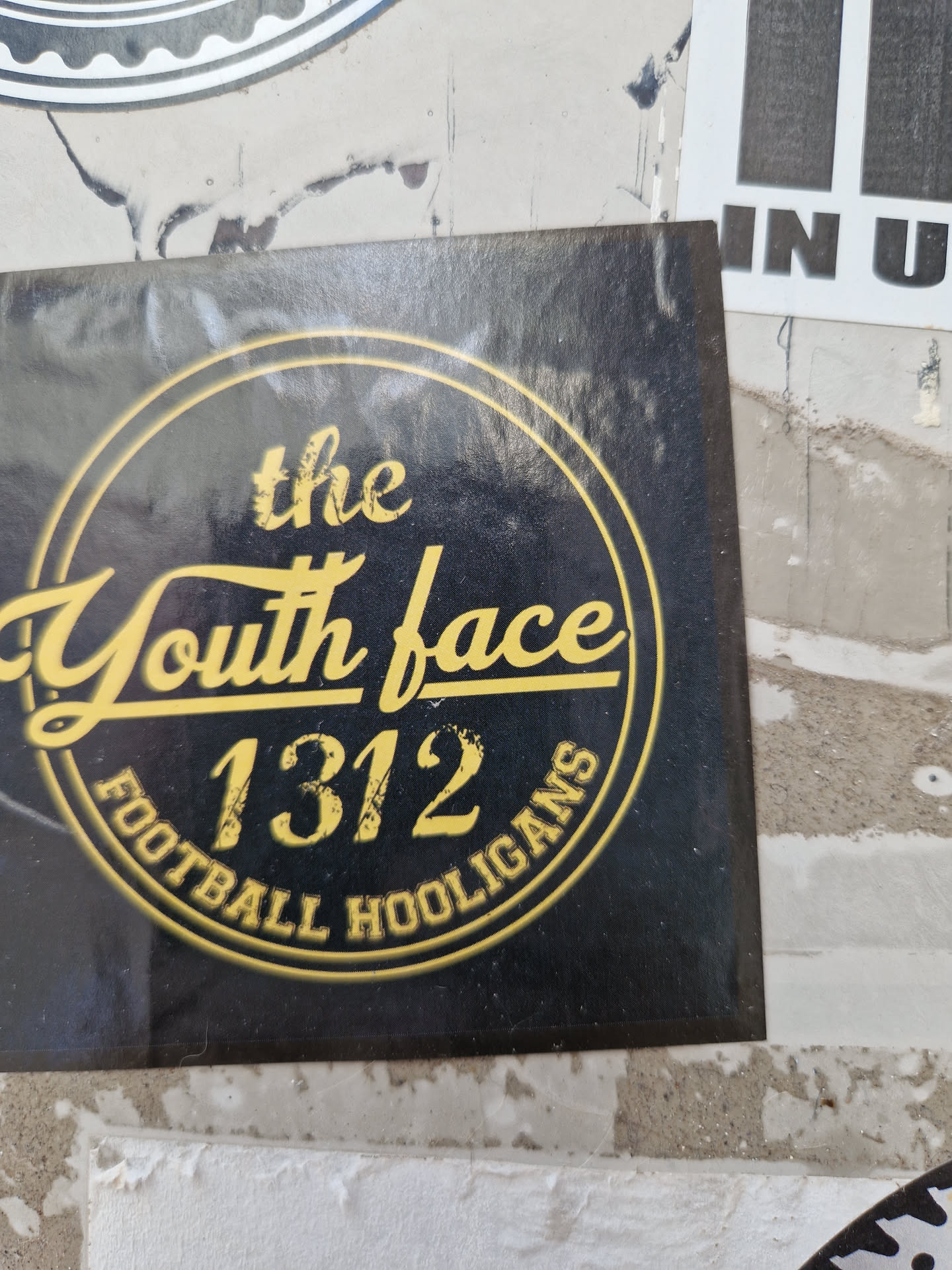 Black and gold sticker with a circular design. The text 'The Youth Face 1312 Football Hooligans' is written in a vintage style font. 