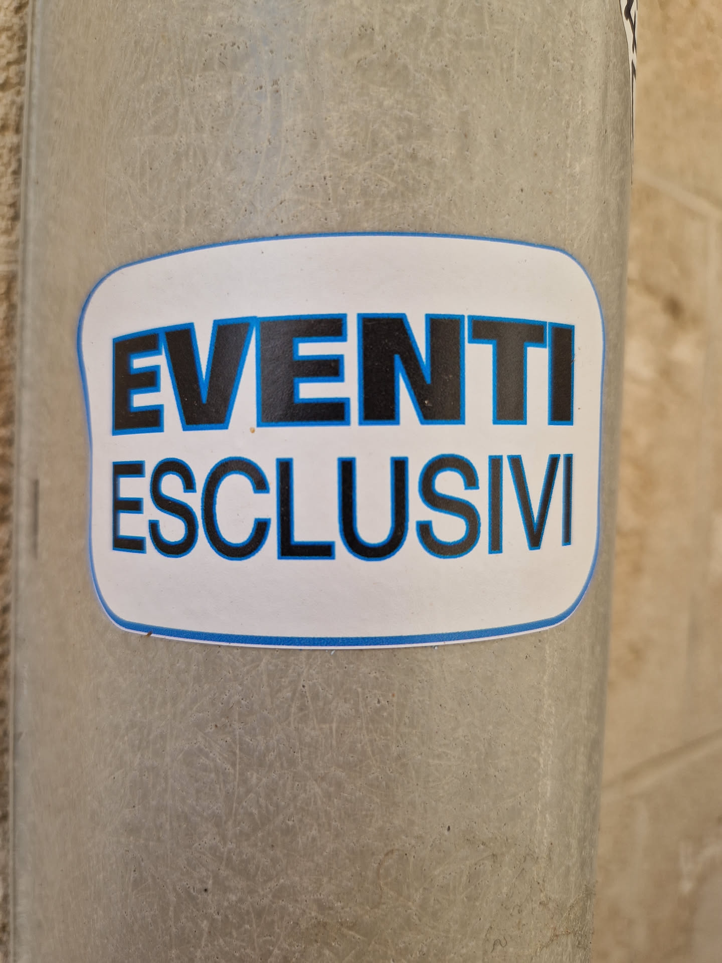 A sticker with the text "EVENTI ESCLUSIVI" which means "Exclusive Events" in Italian. The sticker has a simple design with black text on a white background and a blue border.
