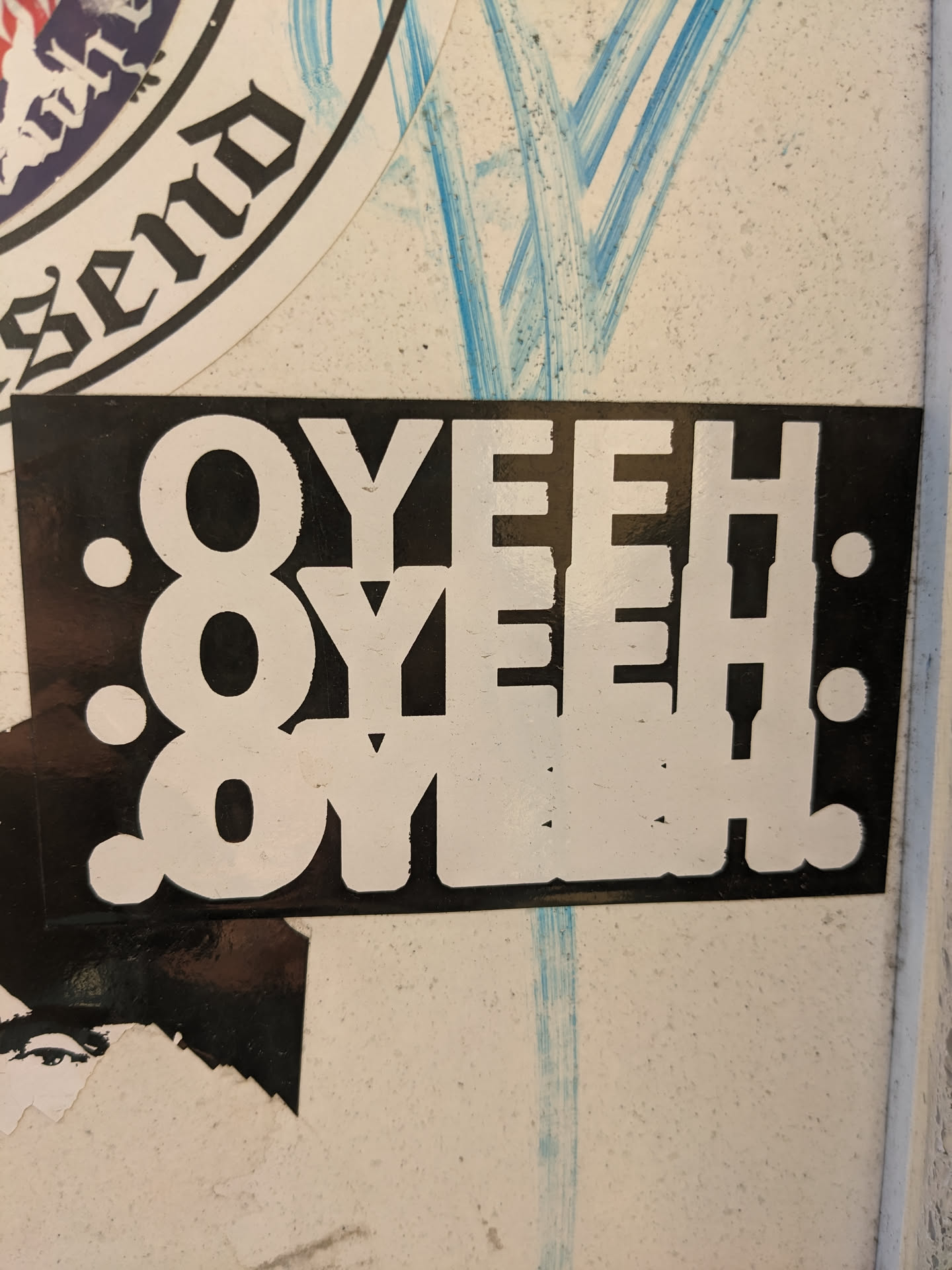 A black and white sticker with the text "OYEH" repeated three times, arranged vertically with slight variations in style. The text is bold and uppercase, printed on a black background with white lettering. The sticker has a simple, graphic design.