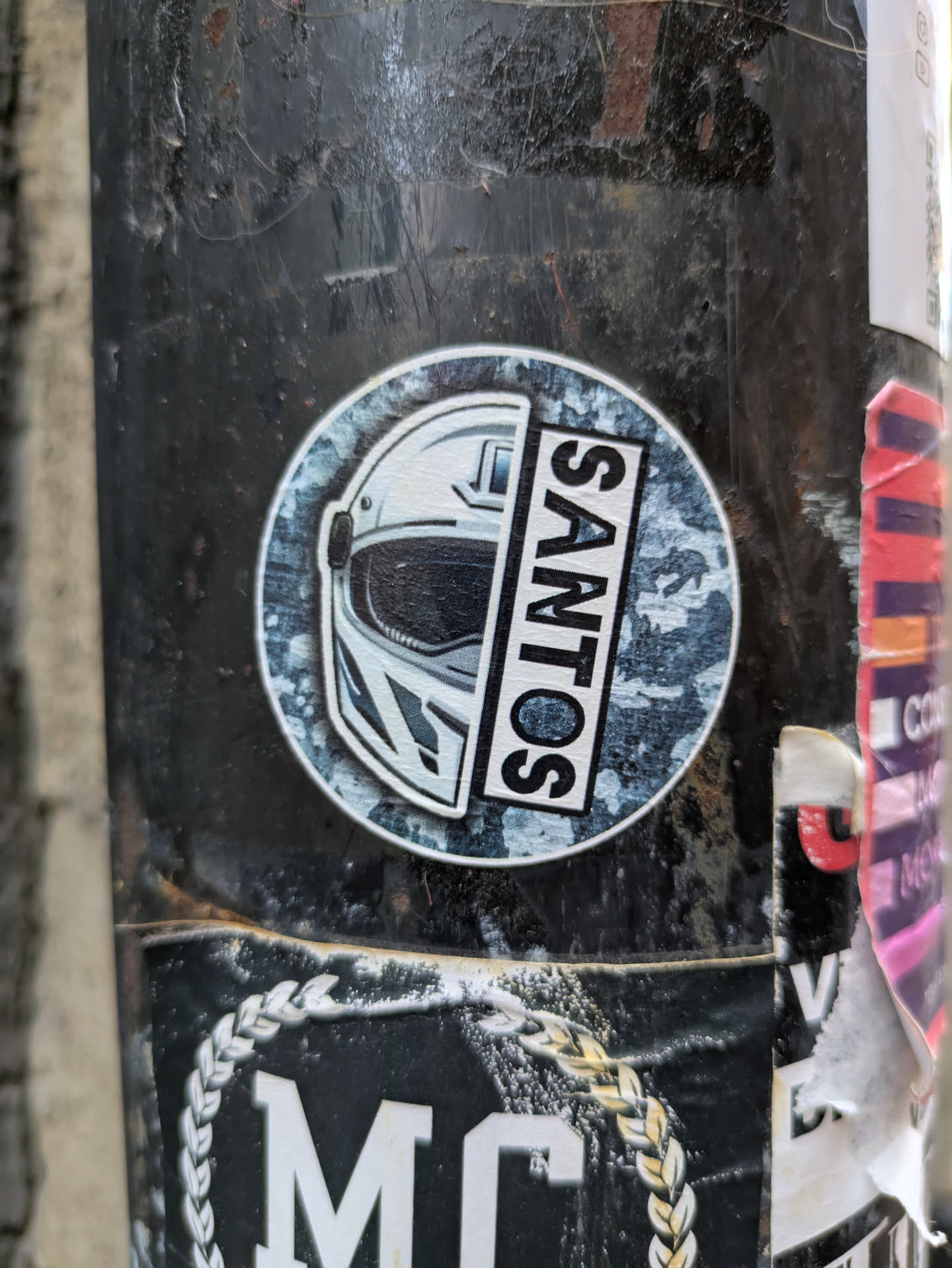 Round sticker featuring a half helmet and the word SANTOS on a camo background.