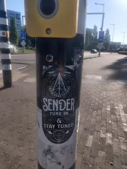Black and white sticker with a vintage design. It features a radio tower graphic, the words "Sender", "Tune In", "&", and "Stay Tuned", and a website address at the bottom. 