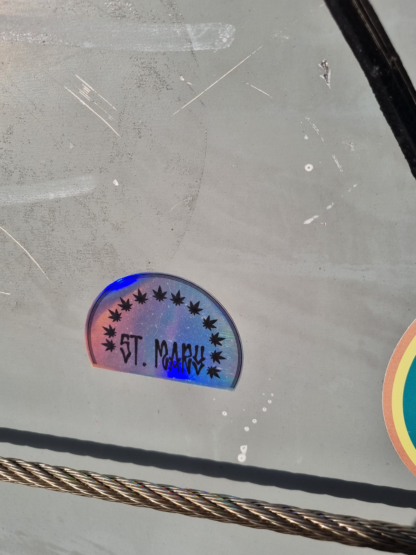 A holographic sticker with a semi-circle design featuring marijuana leaves and the text 'ST. MARY' in the center. The sticker has a rainbow effect.