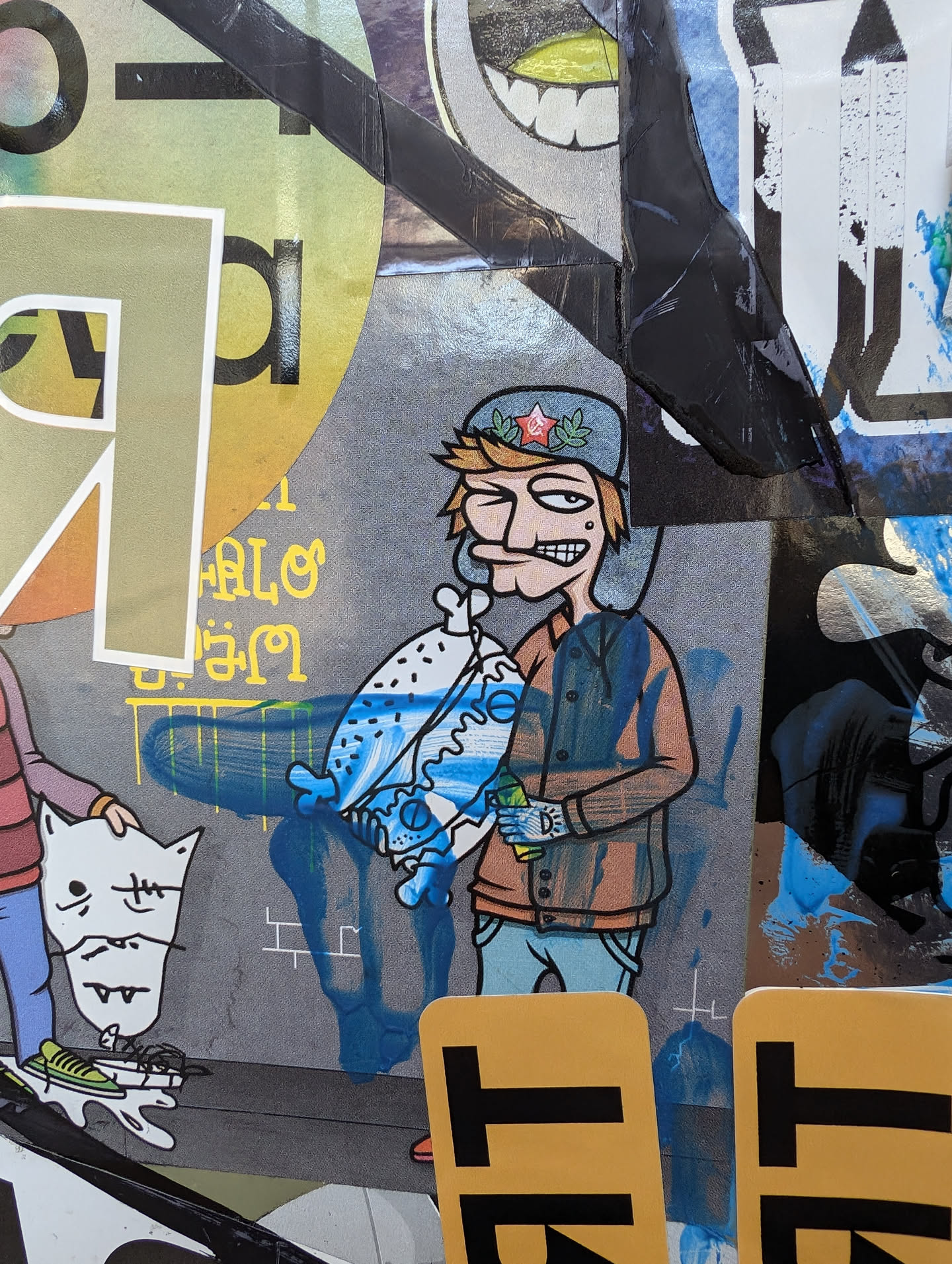A sticker featuring an illustrated character, possibly a cartoon, holding a large, stylized burger. The character is wearing a hat and jacket, and the art style is reminiscent of graffiti or street art. The background shows other stickers and paint splatters.