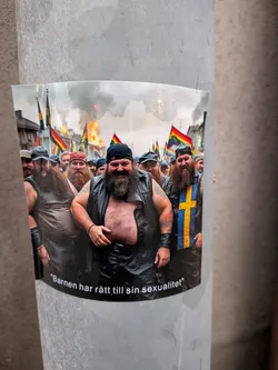 The sticker features a group of men with prominent beards, many wearing leather vests and bandanas, in what appears to be a parade or rally. Several pride flags and a Swedish flag are visible in the background, along with smoke or fire, suggesting a dynamic event. The men are smiling and appear to be in good spirits. The sticker has a curved bottom edge with text.
