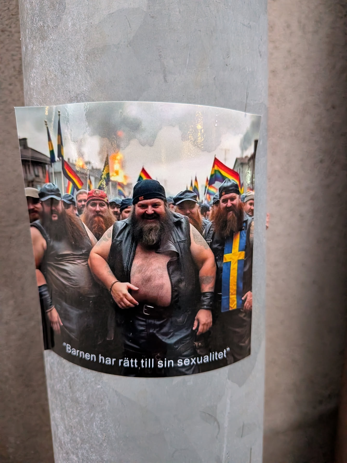 The sticker features a group of men with prominent beards, many wearing leather vests and bandanas, in what appears to be a parade or rally. Several pride flags and a Swedish flag are visible in the background, along with smoke or fire, suggesting a dynamic event. The men are smiling and appear to be in good spirits. The sticker has a curved bottom edge with text.