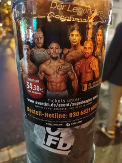 A sticker advertising a Superleague MMA event.  The sticker features several fighters and includes ticket information, a hotline number, and website URL. The logo for the event and the sponsoring company are displayed at the bottom.