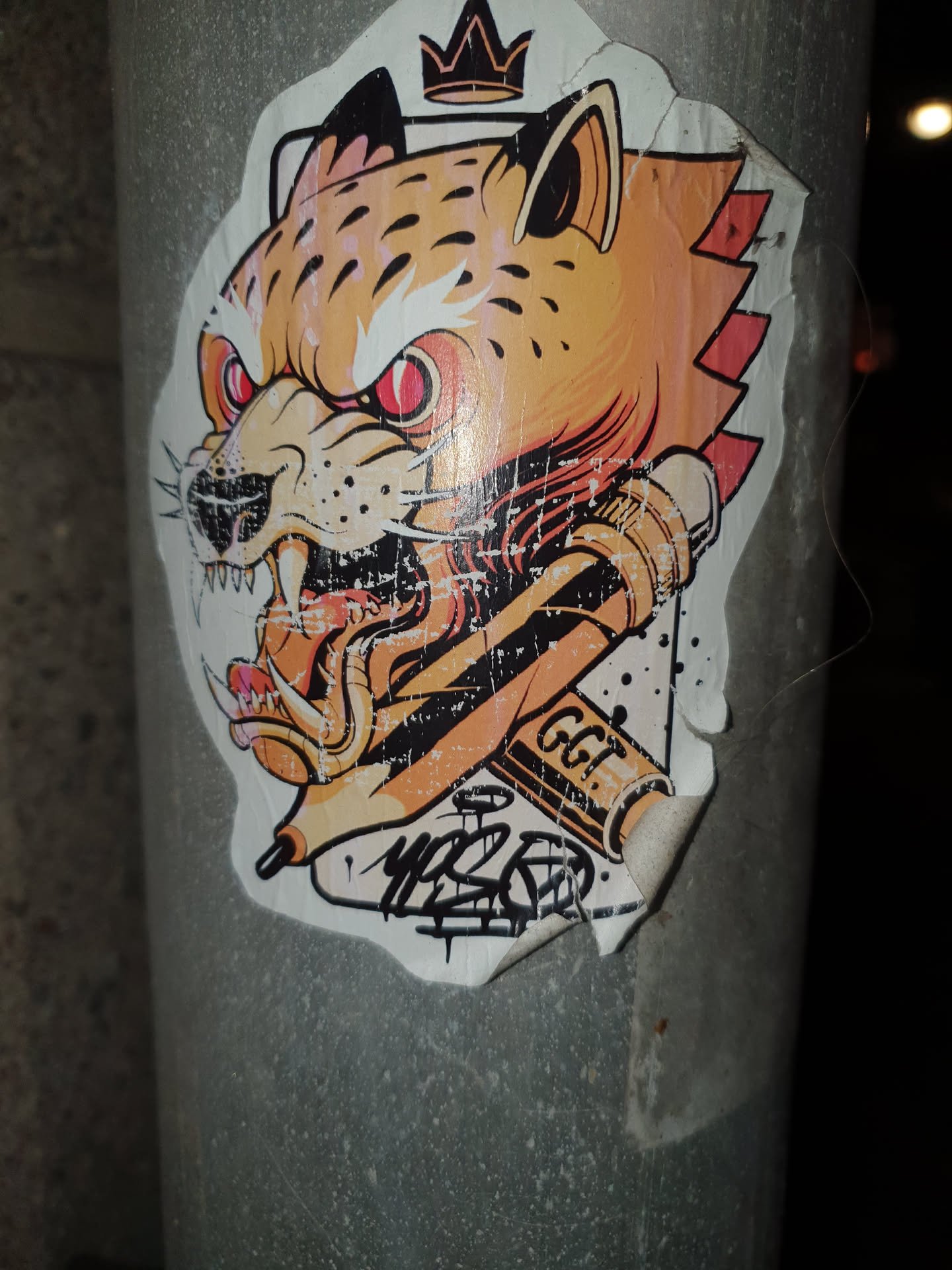 A cool sticker featuring a stylized cheetah wearing a crown and holding two pencils. The art style is bold and graphic, with vibrant colors and a detailed design. The sticker has some minor damage from being peeled and reapplied, adding to its street art aesthetic. There is an artist's signature near the pencils.