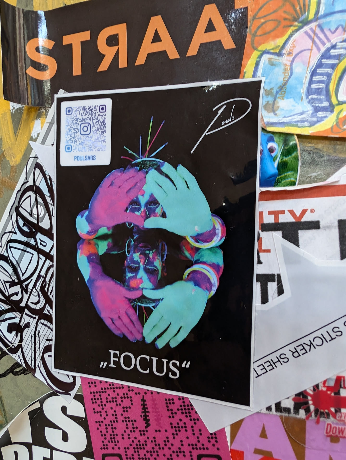 A vibrant sticker featuring a psychedelic illustration of a face surrounded by hands. The artist's signature is visible in the upper right corner, and the word "FOCUS" is written at the bottom. A QR code linking to the artist's Instagram is also included.