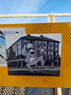 This sticker features a cartoon-like drawing of a man joyfully leaping in front of what seems to be a hotel. The style is reminiscent of vintage illustrations or comic strips. The man is depicted with a beard, a cap, and what looks like a bottle in his hand. The background is a grayscale image of a building named "Stockholmshotellet".