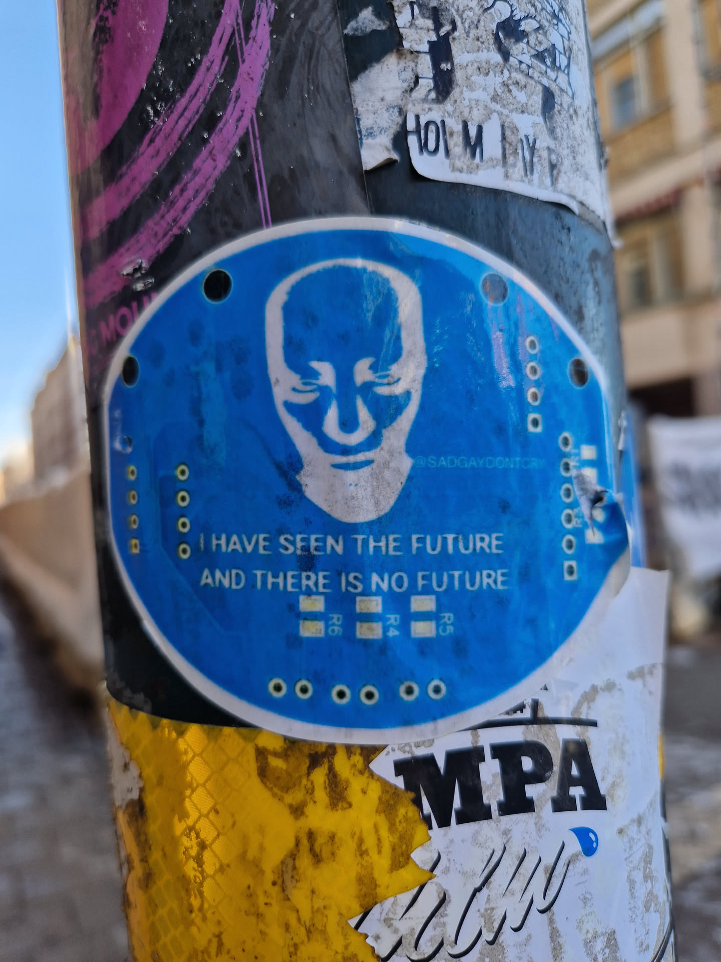 A blue round sticker with a bald head illustration and a text that says: "I have seen the future and there is no future". The sticker also contains a social media handle @sadgaydontcry. 