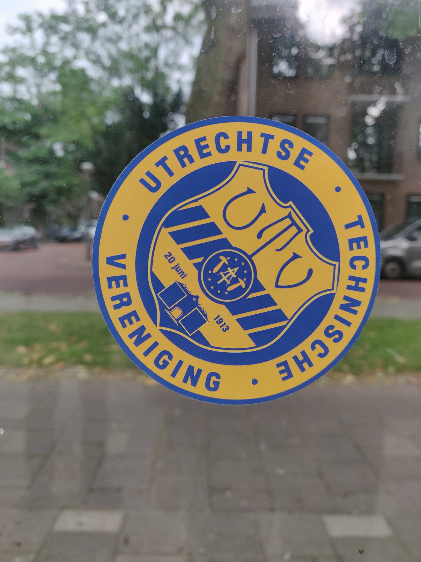 Round sticker with a blue and gold crest. The text around the crest says "UTRECHTSETECHNISCHEVERENIGING". Inside the crest is a smaller logo with text that includes "20 juni" and "1913".