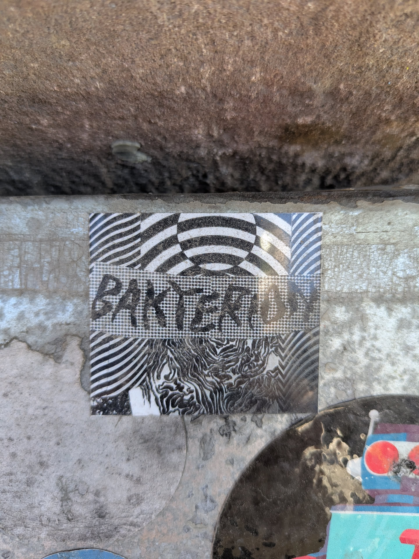 The sticker is divided into sections with alternating black and white patterns. The word "BAKTERIUM" is written across the center section in a stencil-like font. The patterns include wavy lines, checkered patterns, and other abstract designs.
