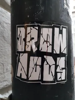 Black and white sticker with the text "DRAW A LINE" in a cracked style. The sticker has a square shape and a distressed effect, giving it a gritty, urban feel.