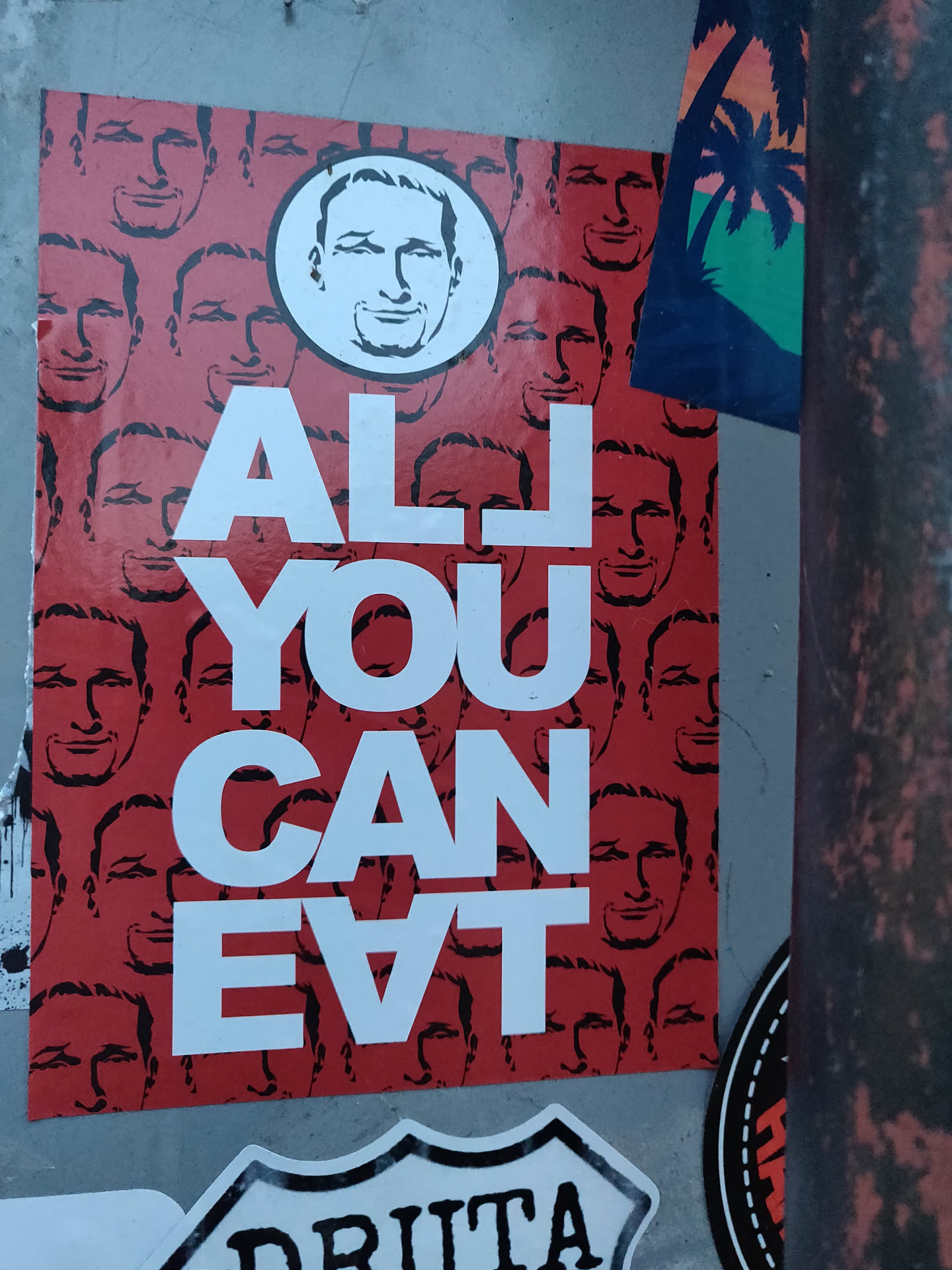 A sticker with the text "ALL YOU CAN EAT" in bold white letters on a red background. The background is filled with repeating images of the same man's face. A larger circle version of the man's face is featured at the top. 