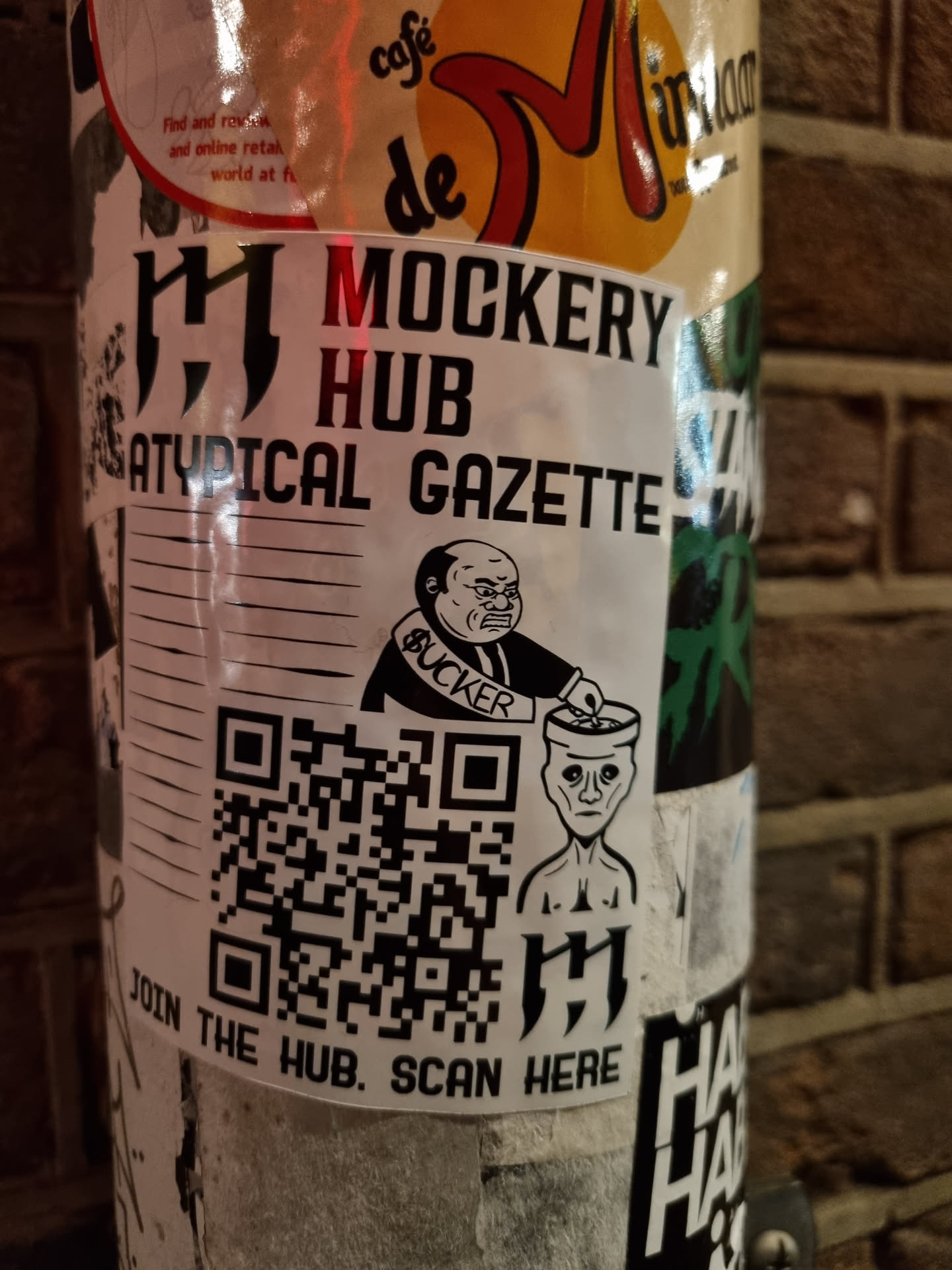 A sticker featuring the logo for the Mockery Hub, a satirical publication. The sticker includes a QR code that directs users to join the hub.
