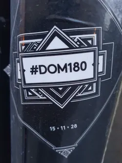 Black and white sticker with a geometric design and the text #DOM180. The date 15.11.28 is also visible.