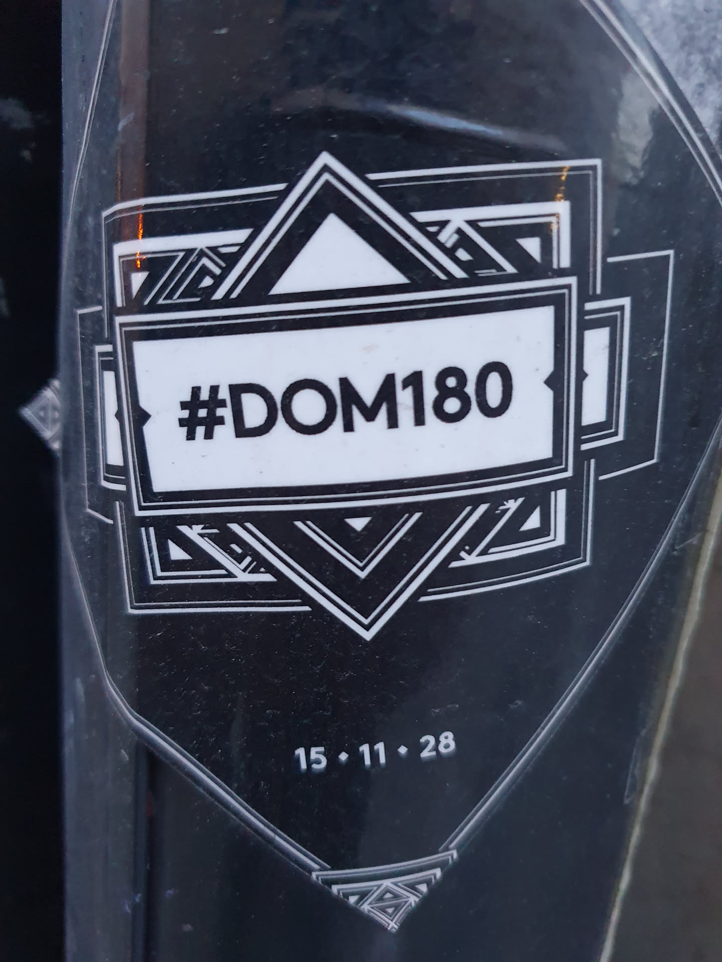 Black and white sticker with a geometric design and the text #DOM180. The date 15.11.28 is also visible.