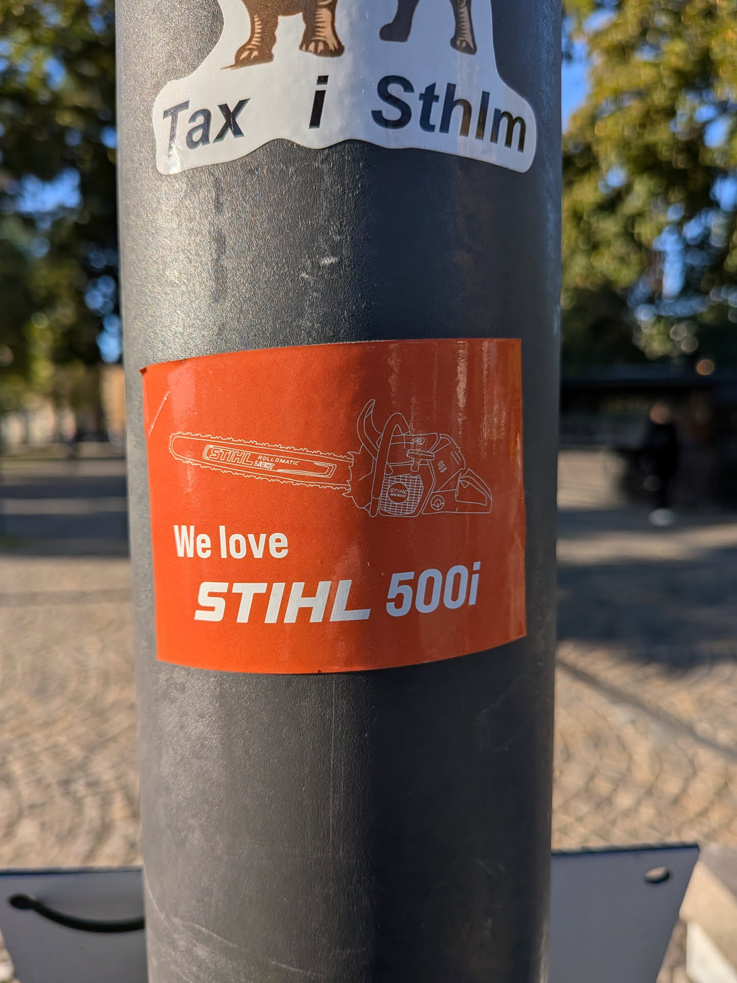 The sticker is rectangular with a rounded corner and has a bright orange background. It features a white outline drawing of a STIHL chainsaw, specifically the 500i model, prominently displayed in the upper half. Below the chainsaw illustration, the text 'We love' is written in white, followed by 'STIHL 500i' in large, bold white capital letters.