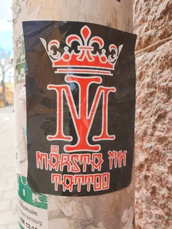 Black and red sticker with a crown and the letters M and I. Below is the text "Mörsta Ink Tattoo".