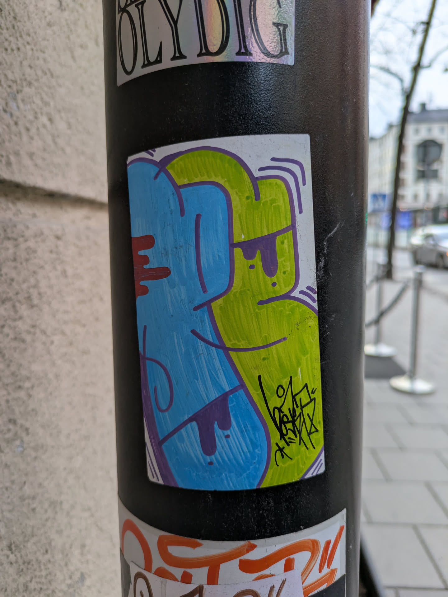 This sticker features a unique design with blue and green colors, accented with purple and red. It's a hand-drawn graffiti style artwork.