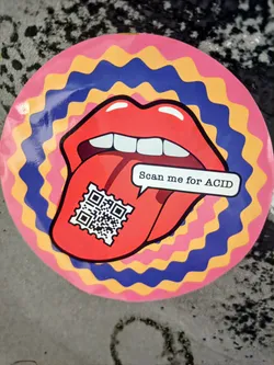 Round sticker featuring a tongue with a QR code. The design is psychedelic with pink, yellow, and blue wavy circles.