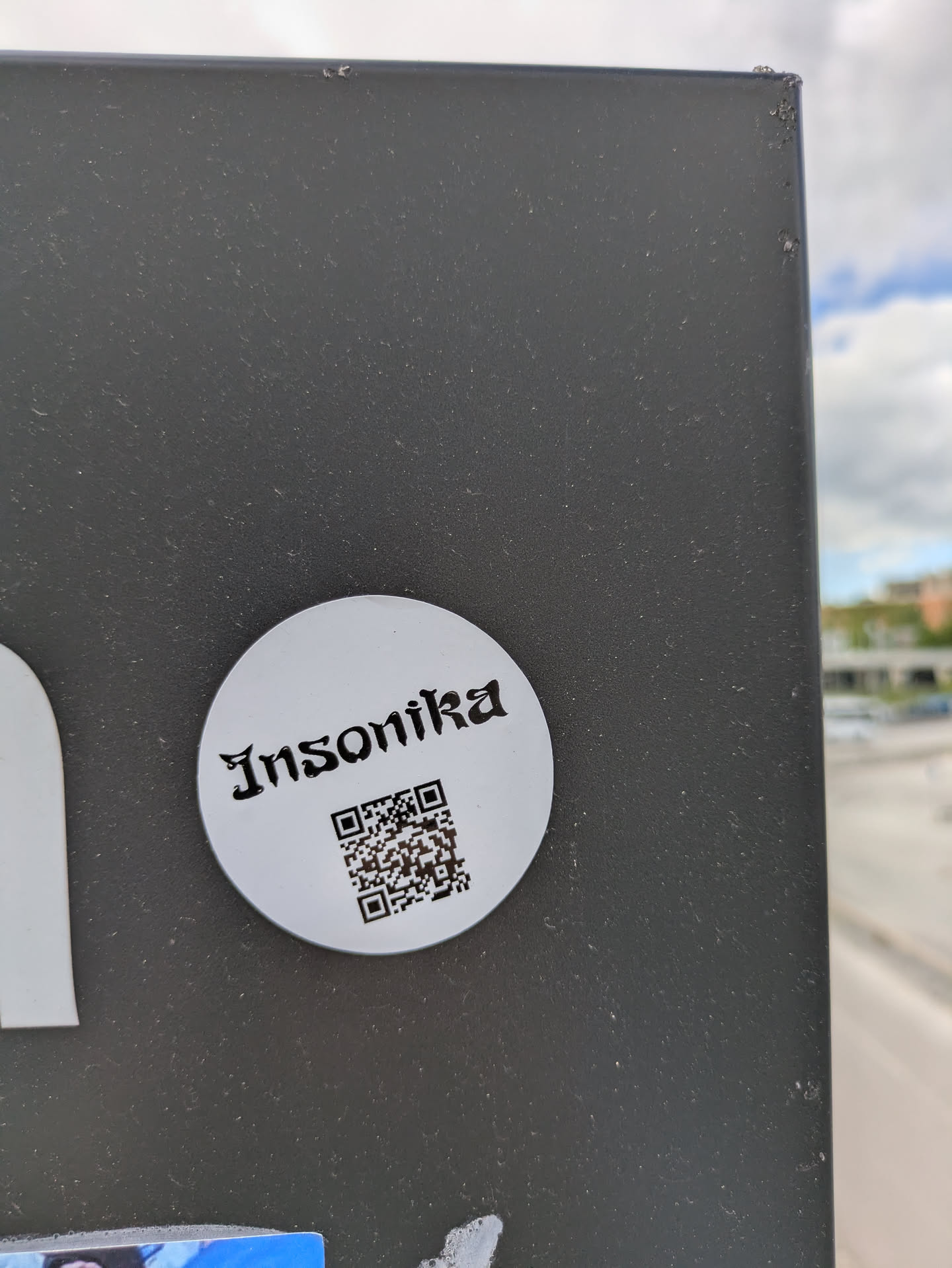 The sticker is a white circle with the text "Insonika" in a gothic style font at the top. Below the text is a QR code.