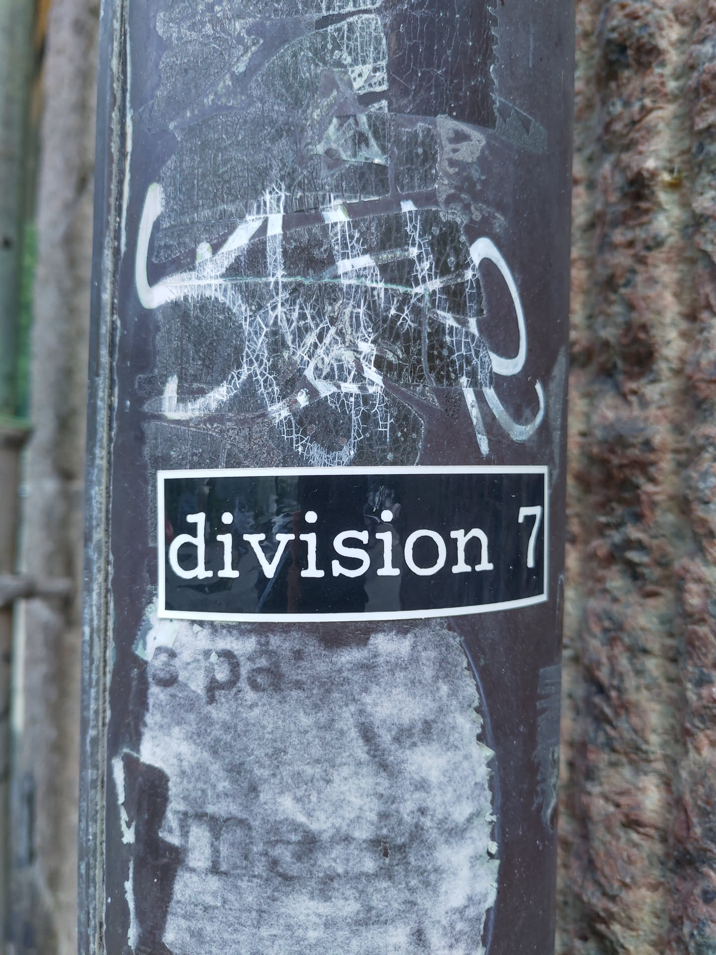 A black and white sticker with the text "division 7" on a dark background attached to a pole.