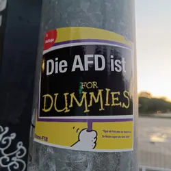 A sticker with a black background and yellow border. It says in German: "Die AFD ist for Dummies" which translates to "The AFD is for Dummies". There is also a smaller text at the bottom that seems to be a quote.