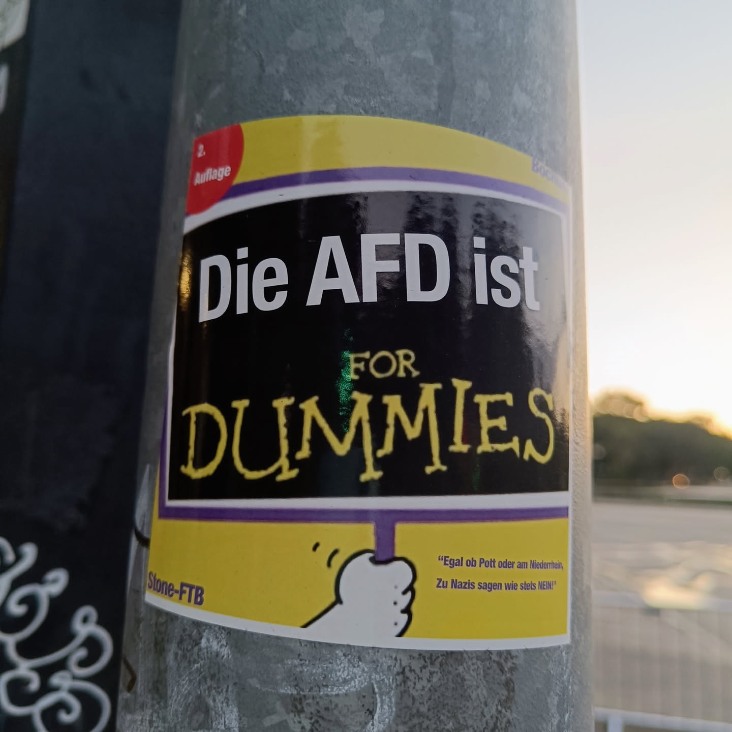 A sticker with a black background and yellow border. It says in German: "Die AFD ist for Dummies" which translates to "The AFD is for Dummies". There is also a smaller text at the bottom that seems to be a quote.