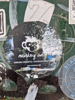 Round sticker with a monkey illustration and a forest background. Contains the website and social media links for Monkey Art, which offers web design, advertising materials, graphic design, video and photography services.