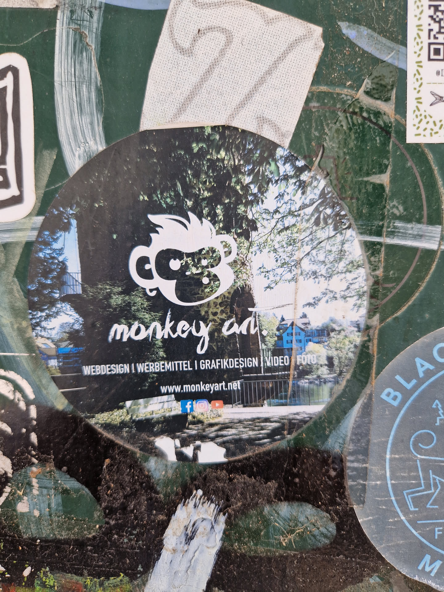 Round sticker with a monkey illustration and a forest background. Contains the website and social media links for Monkey Art, which offers web design, advertising materials, graphic design, video and photography services.