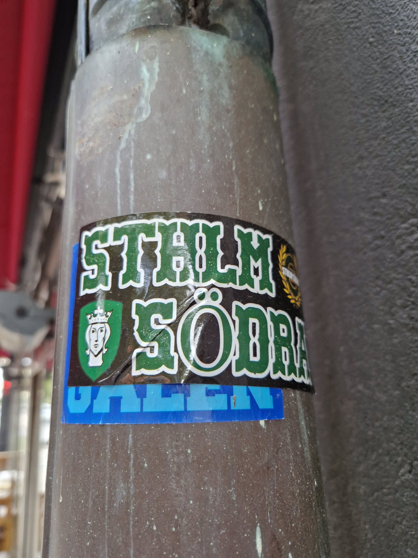 A sticker featuring the text "STHLM SÖDRA GÅLLEN" in green and blue lettering.  A crest with a crowned figure is also visible on the sticker.