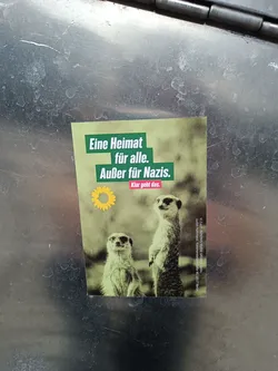 A sticker featuring two meerkats and a message in German that translates to 'A home for everyone. Except for Nazis. It's clear that it works.'