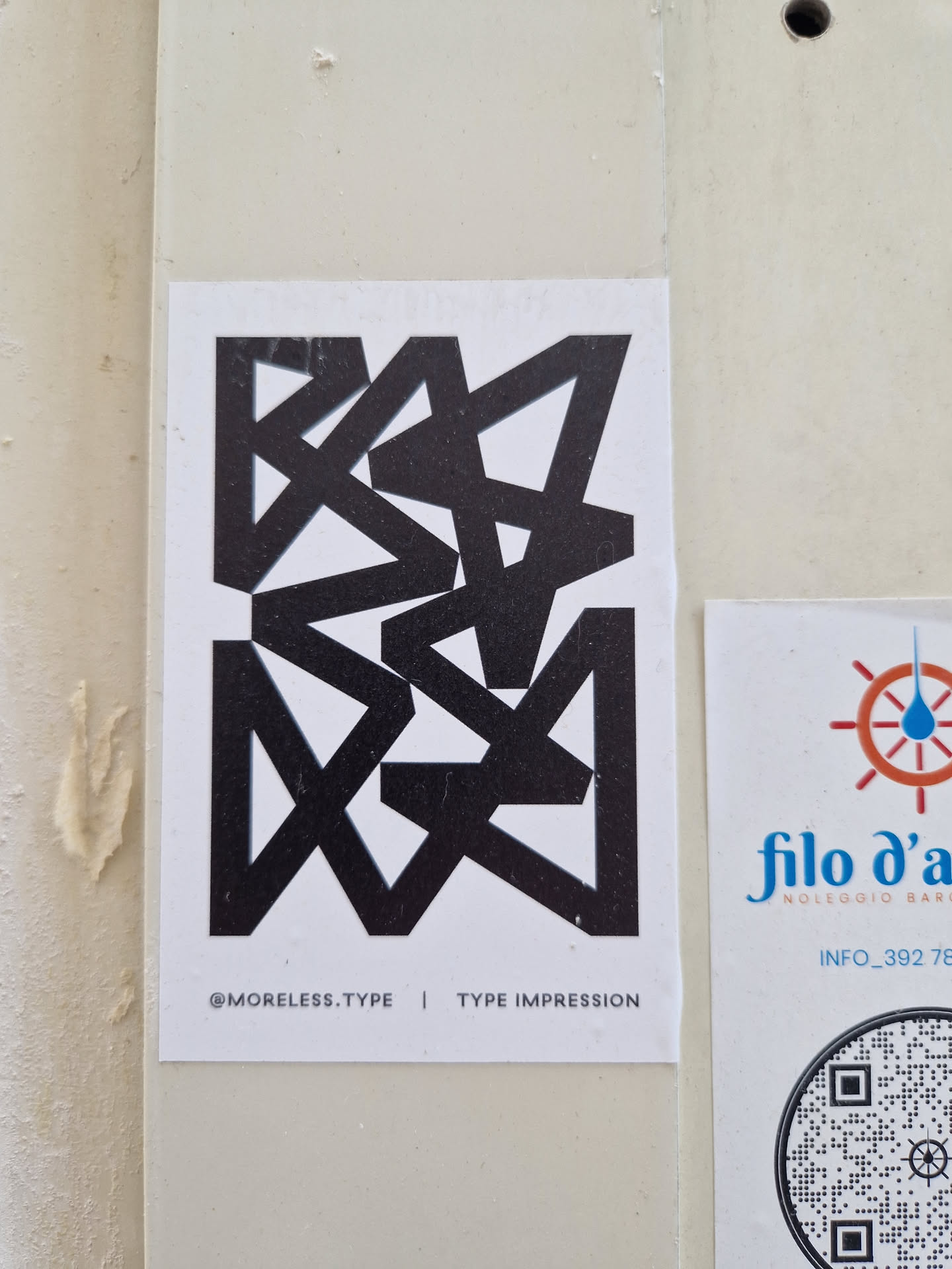 A black and white sticker featuring an abstract geometric design. The text '@moreless.type | TYPE IMPRESSION' is visible at the bottom. 