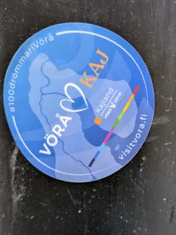 The sticker is round with a blue background and features a stylized map of the Vorå region. The text includes the names of cities and regions, and a URL to a tourism website.