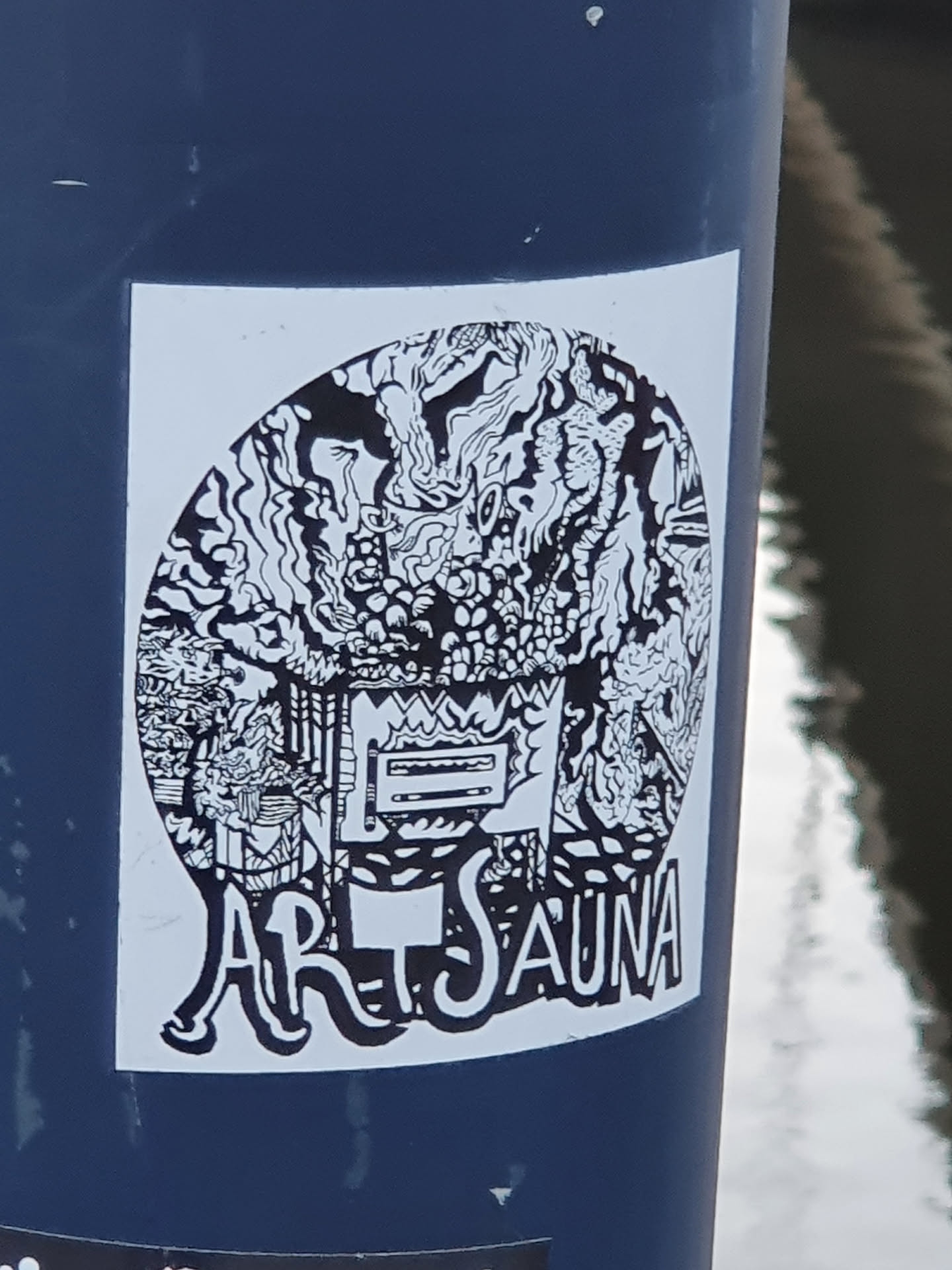 Black and white illustration sticker with the text "Art Sauna" at the bottom. The illustration contains abstract shapes and patterns, resembling a stylized sauna scene.